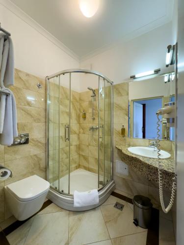 a bathroom with a shower and a toilet and a sink at Hotel Polonia in Kraków