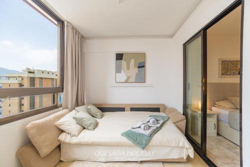 a bedroom with a bed and a large window at Oasis Levante Beach Benidorm - Trinisol II in Benidorm