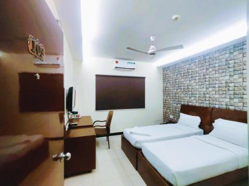 a hotel room with two beds and a flat screen tv at Athasri Hotel Infantry Road in Bengaluru