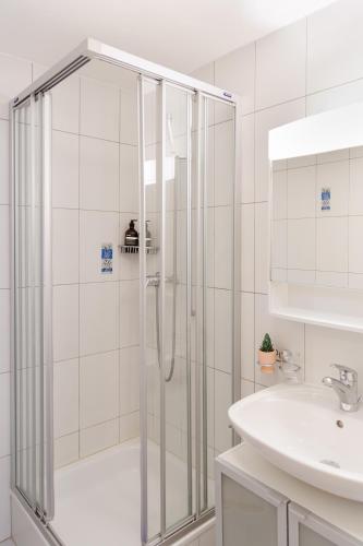 a white bathroom with a shower and a sink at Haus Snow Fun B in Saas-Fee