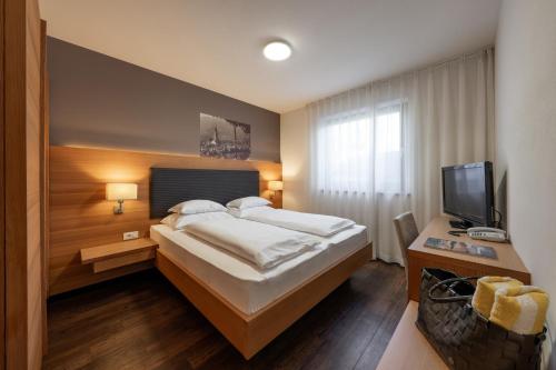 a hotel room with a bed and a television at Alagundis Apartment Residence in Lagundo