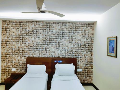 two beds in a room with a brick wall at Athasri Hotel Infantry Road in Bengaluru