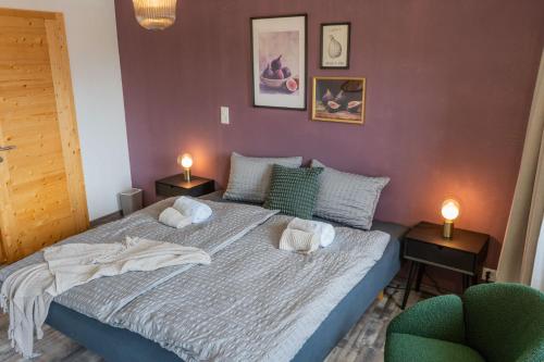 a bedroom with a bed with two lamps and two chairs at BnB Feuille de Vigne in Saint-Léonard