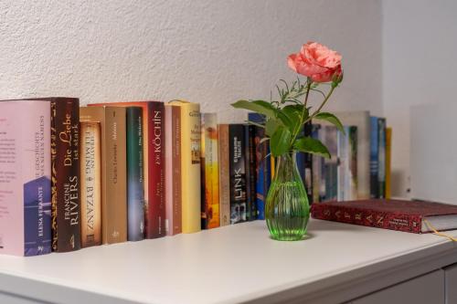 a vase with a rose on a shelf with books at BnB Feuille de Vigne in Saint-Léonard