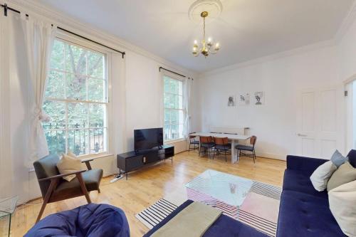a living room with a blue couch and a table at Spacious 3BDR-Steps To Kings Cross Tube in London