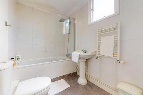 a white bathroom with a toilet and a sink at Spacious 3BDR-Steps To Kings Cross Tube in London