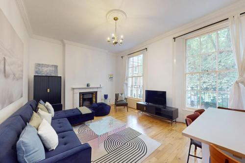 a living room with a blue couch and a fireplace at Spacious 3BDR-Steps To Kings Cross Tube in London