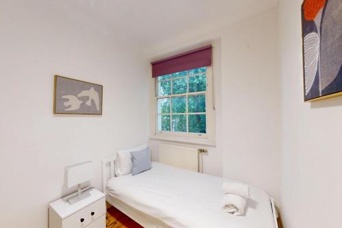 a small bedroom with a bed and a window at Spacious 3BDR-Steps To Kings Cross Tube in London
