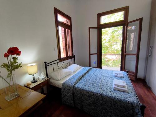 a bedroom with a bed with a blue comforter and two windows at JP Castle Resort in Chios