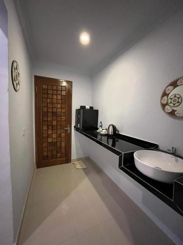 a bathroom with a sink and a microwave at Gamat Sunset Cottage and Resto in Nusa Penida