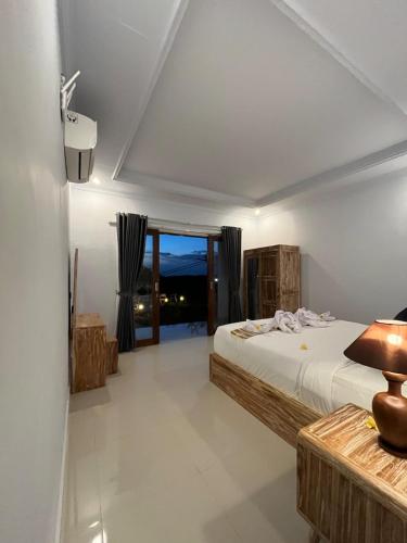 a bedroom with a bed and a large window at Gamat Sunset Cottage and Resto in Nusa Penida