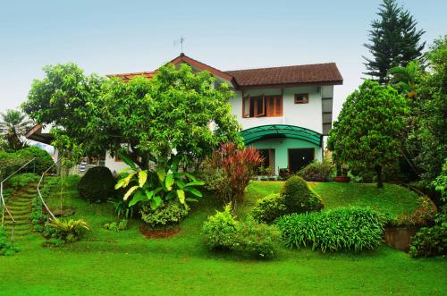a house with a green yard with trees and bushes at Villa Buenavista Puncak in Puncak
