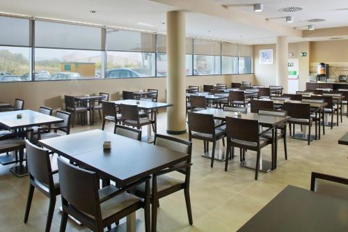 a dining room with tables and chairs and windows at Holiday Inn Express Campo de Gibraltar-Barrios by IHG in Los Barrios