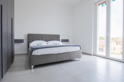 デセンツァーノ・デル・ガルダにあるvicino al lago, Casa Leonardoのベッドと大きな窓のある寝室