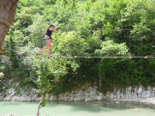 a woman walking across a rope bridge over a river at Libera Mente in Fabriano