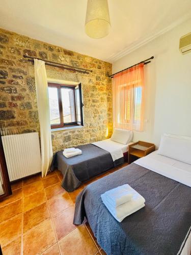 a room with two beds and a brick wall at Mani Spot Sunset View in Areopoli