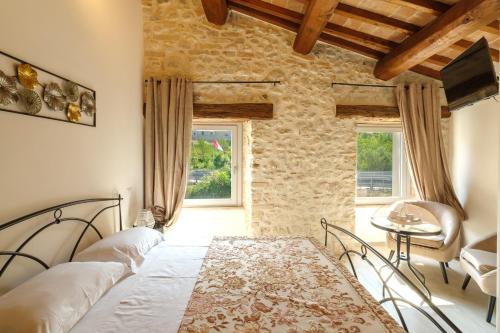 a bedroom with a bed and a table and two windows at Le Camere di Stefano - Spoleto in Spoleto