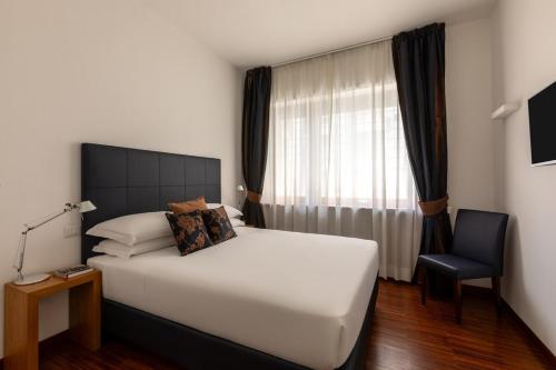 una camera da letto con un grande letto bianco e una sedia di Casa Sacchi by Hili a Roma