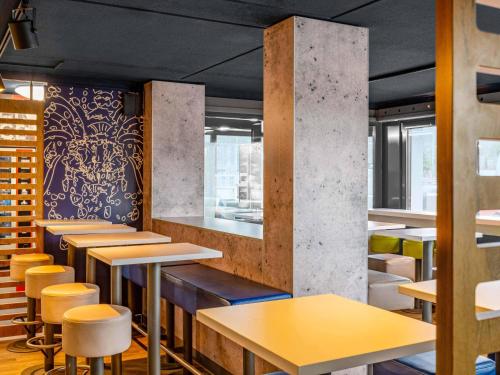 a restaurant with tables and stools in a room at B&B HOTEL Aachen-Nord in Aachen