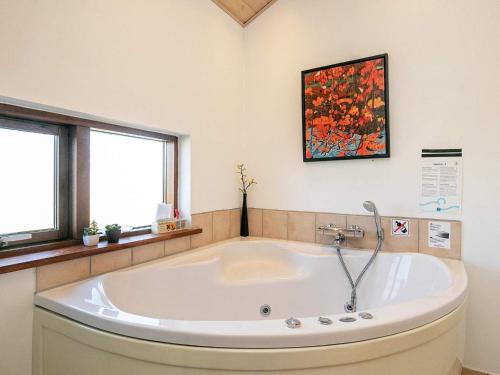 a large white tub in a bathroom with two windows at Panoramic Seaside Retreat - By Traum Ferienwohnungen in Thorsminde