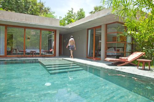 a man standing next to a house with a swimming pool at Templation Hotel in Siem Reap