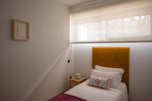a small bedroom with a bed and a window at Casa d'Abreu Neto - Siza's First Work in Matosinhos