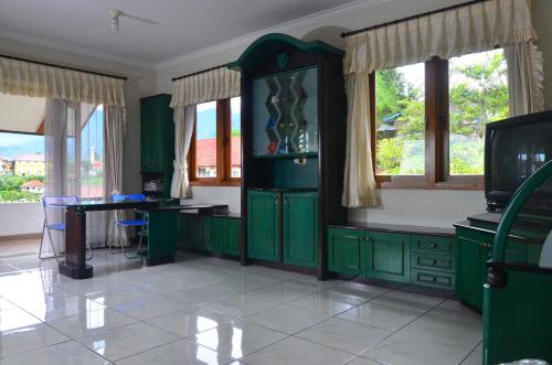 a kitchen with green cabinets and a table and a tv at Villa Buenavista Puncak in Puncak