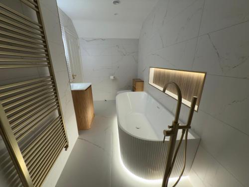 a bathroom with a white tub and a sink at Peace Cottage in Darlington