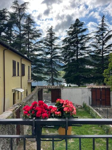 a table with red flowers on top of a fence at Piediluco House - La Casa di Caio in Piediluco