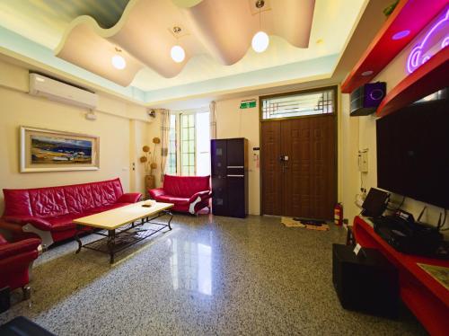 a living room with a red couch and a table at 小熊城堡民宿-免費停車 !!新歌KTV-過山車電動麻將-露天烤肉-以上設備僅限包棟使用 # 選Villa才是包棟 # - 16人以下可少人包棟請電聯!! in Hualien City