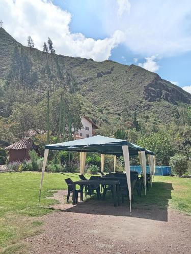 a picnic table with a blue canopy in a field at EColodge Ccatan in Urubamba