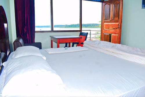 two beds in a room with a table and a window at Hotel Gourav in Havelock Island