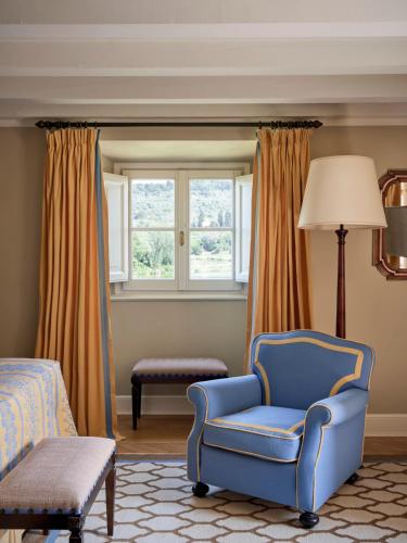 a bedroom with a blue chair and a window at Villa La Massa in Bagno a Ripoli