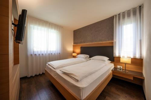 a bedroom with a large bed and a television at Alagundis Apartment Residence in Lagundo