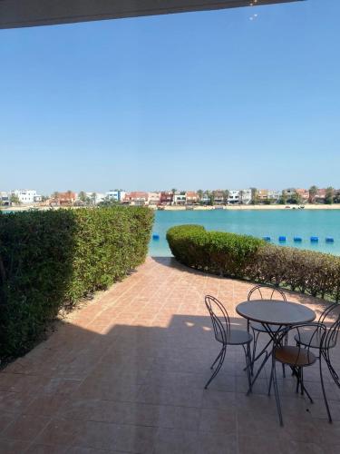 a patio with a table and chairs next to the water at شالية درة العروس in Durat  Alarous