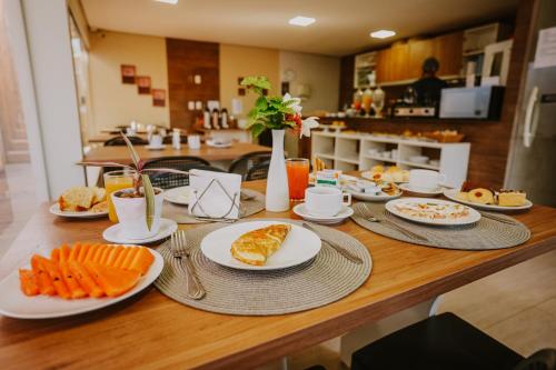a wooden table with plates of food on it at Pousada Aconchego Noronha in Fernando de Noronha