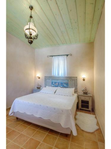 a bedroom with a white bed and a chandelier at Pandora in Pirgos Dhirou