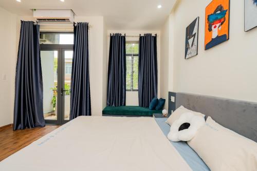 a bedroom with a white bed and a green chair at Aluna Residence Homestay in Da Nang
