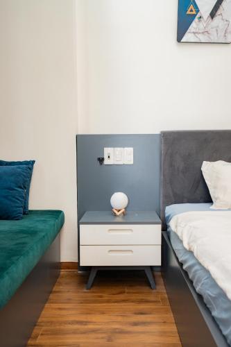a bedroom with a bed and a nightstand with a green couch at Aluna Residence Homestay in Da Nang