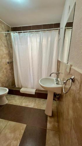 a bathroom with a sink and a shower and a toilet at Tata Inti Complejo Serrano in Merlo