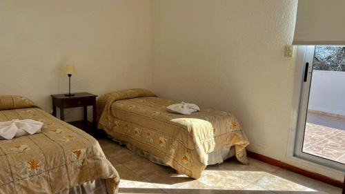 a room with two beds and a window at Tata Inti Complejo Serrano in Merlo