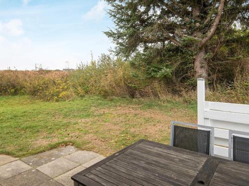 a wooden table and a bench next to a field at 4 person holiday home in Rømø in Lakolk