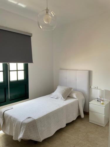 プエルト・デル・ロサリオにあるCasa Maheの白いベッドルーム(ベッド1台、ランプ付)