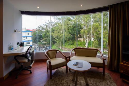 Una sala de estar con una mesa y sillas y una gran ventana. en Emerald Hotel, en Āīzawl