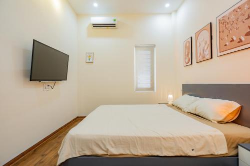 a bedroom with a bed and a flat screen tv at Aluna Residence Homestay in Da Nang