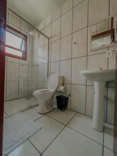 a bathroom with a toilet and a sink at Hotel Girassol in Imbé