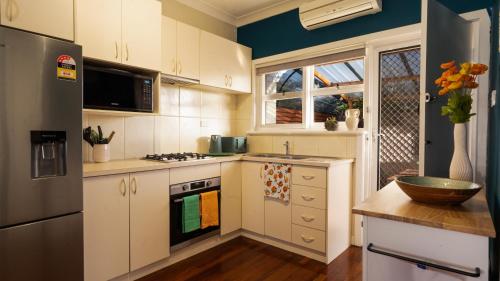 a kitchen with white cabinets and a black refrigerator at Cozy home near Swan River-10 mins to Perth City in Perth