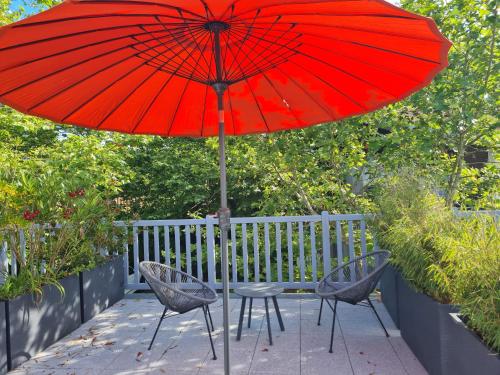 a table and two chairs under a red umbrella at L'Expression in Saint-Jean-de-Marsacq