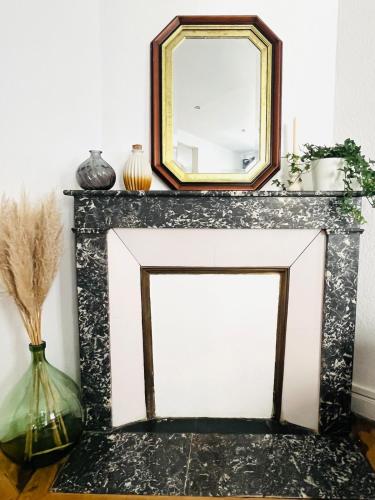 a mirror on top of a fireplace with vases at Appartement Verdun in Verdun