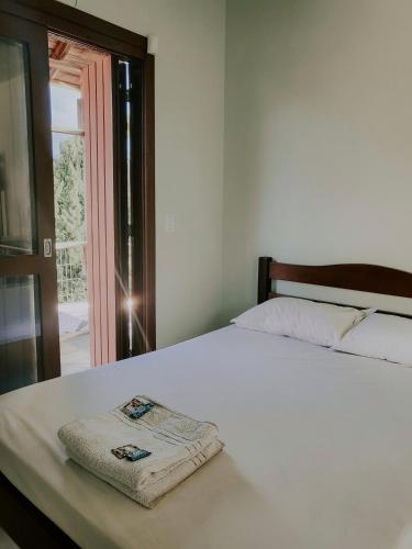 a bedroom with a white bed with a towel on it at Hotel Girassol in Imbé
